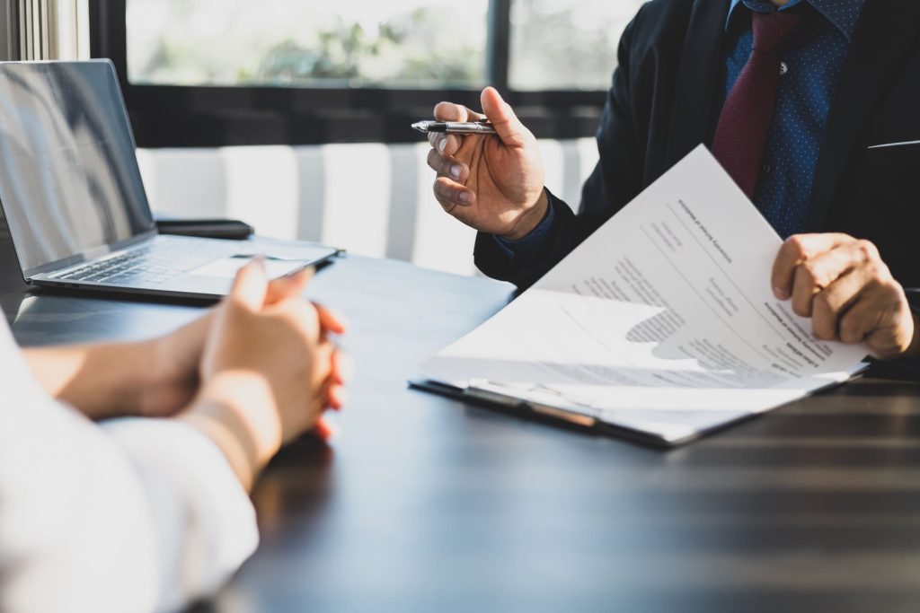 Courtier en assurances expliquant une offre personnalisée à un client lors d'un rendez-vous.