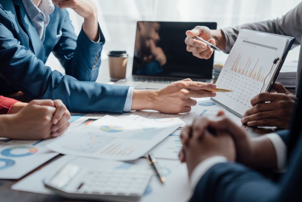 Conseillers analysant des graphiques financiers et des performances d'investissement lors d'une réunion de placement.