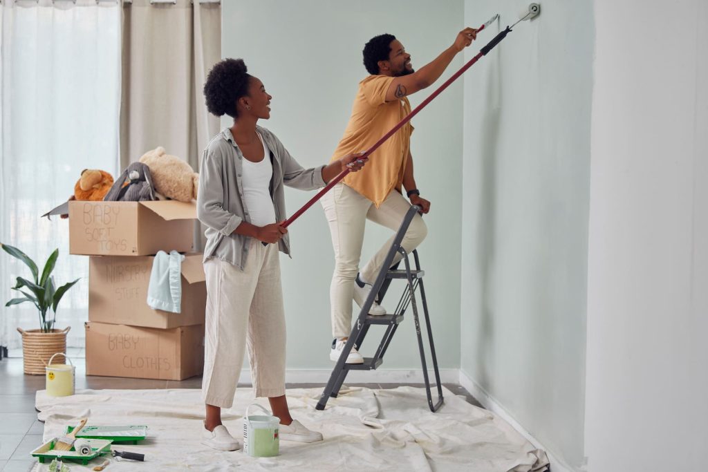 Couple réalisant des travaux de peinture dans leur maison, illustrant un projet de rénovation financé par un crédit rénovation.